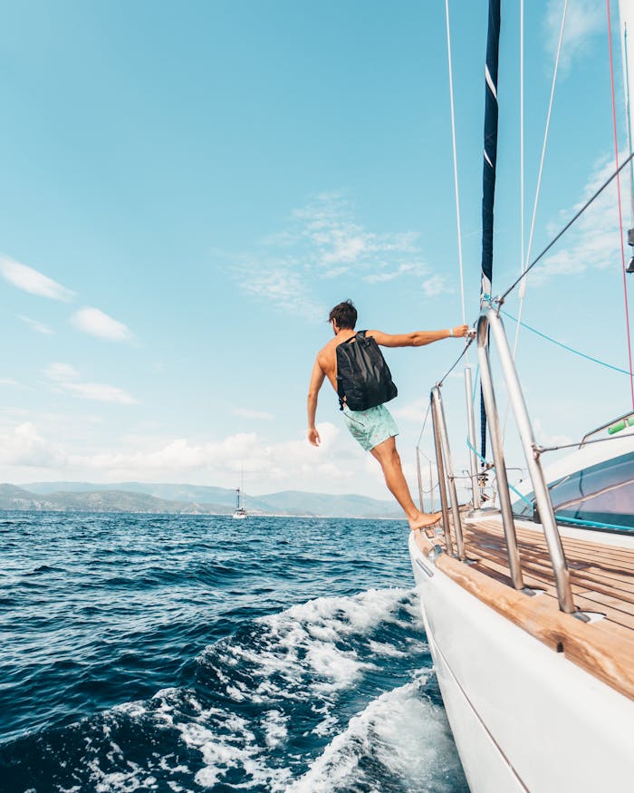 Man sailing in vibrant Greek waters, depicting freedom and adventure under clear skies.