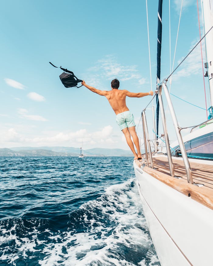 Man enjoying freedom by jumping into the ocean from a sailboat in Greece.